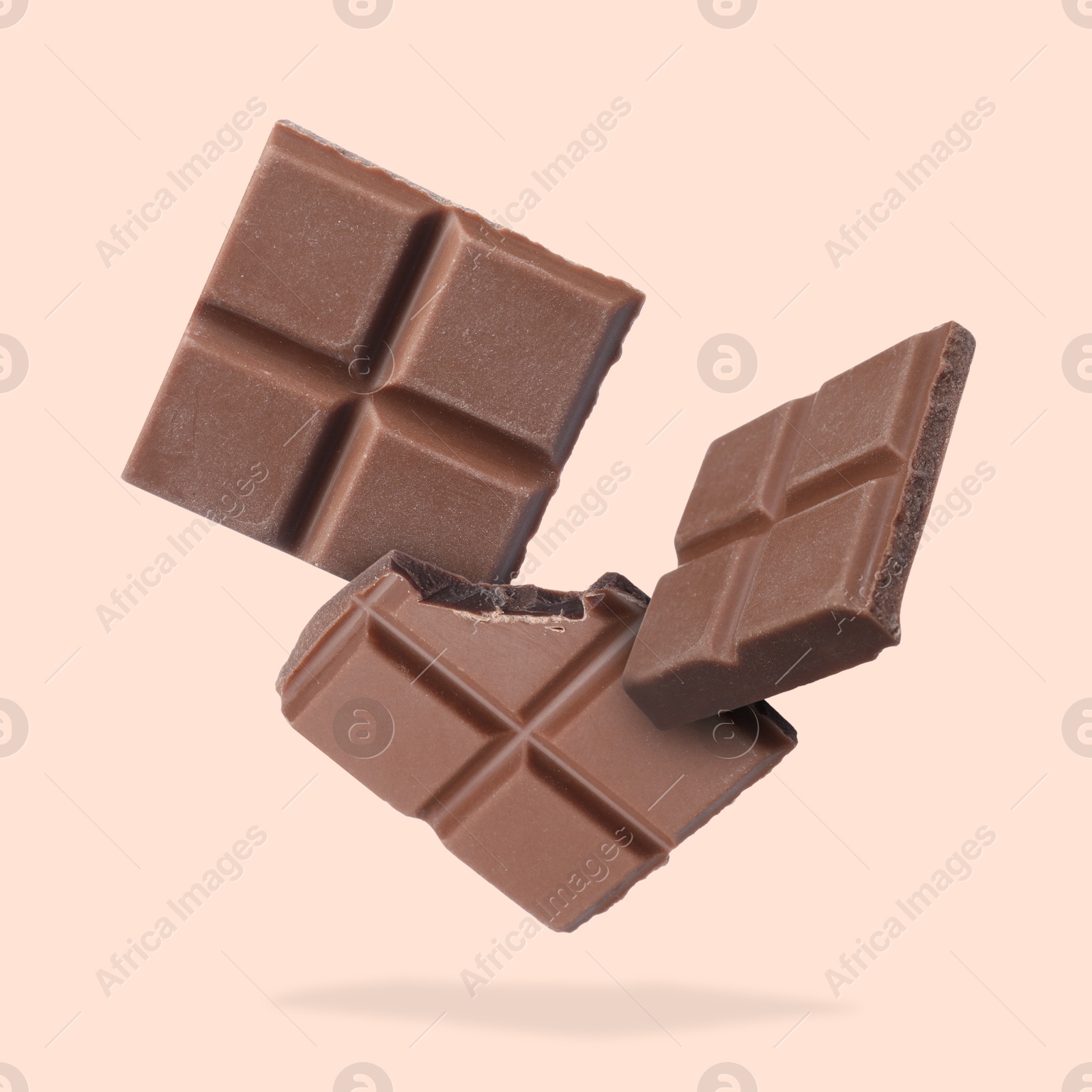 Image of Pieces of sweet chocolate falling on beige background