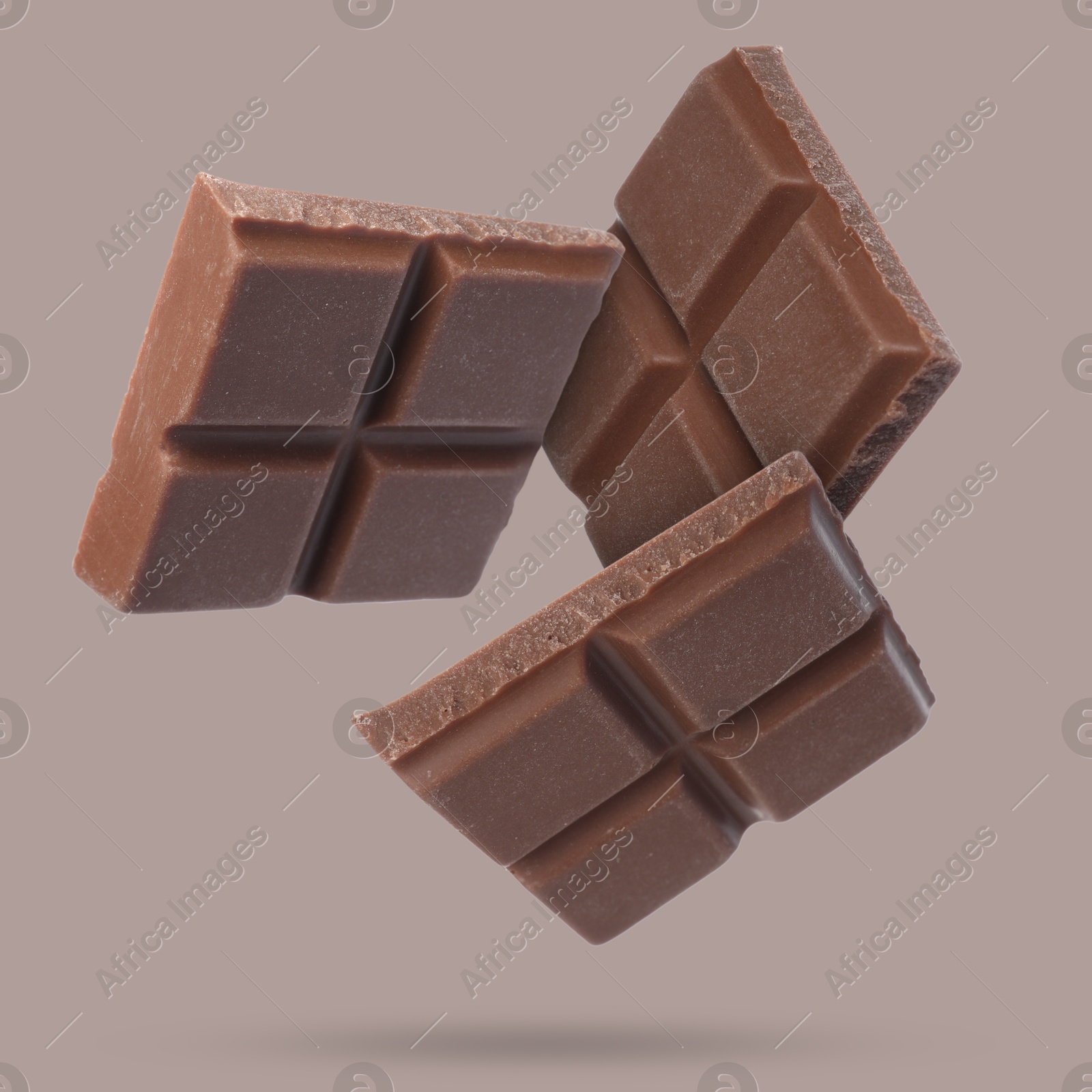 Image of Pieces of sweet chocolate falling on color background