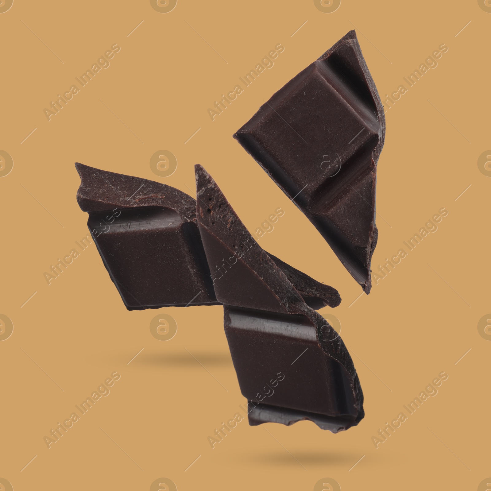 Image of Pieces of sweet chocolate falling on color background