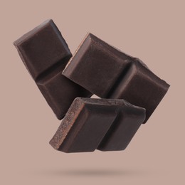 Image of Pieces of sweet chocolate falling on color background