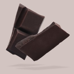 Image of Pieces of sweet chocolate falling on beige background