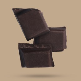 Image of Pieces of sweet chocolate falling on color background