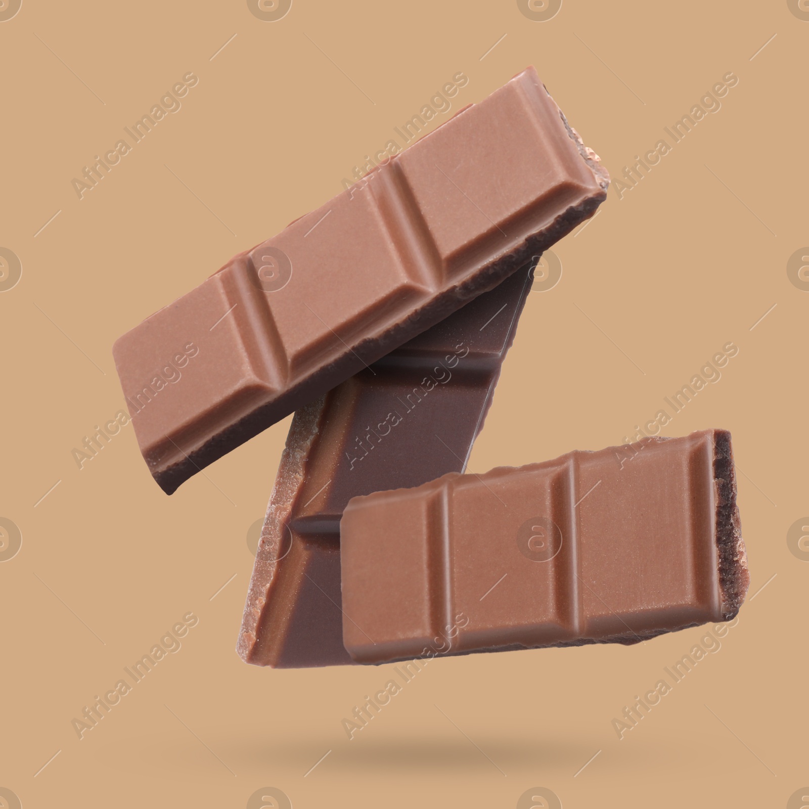 Image of Pieces of sweet chocolate falling on dark beige background