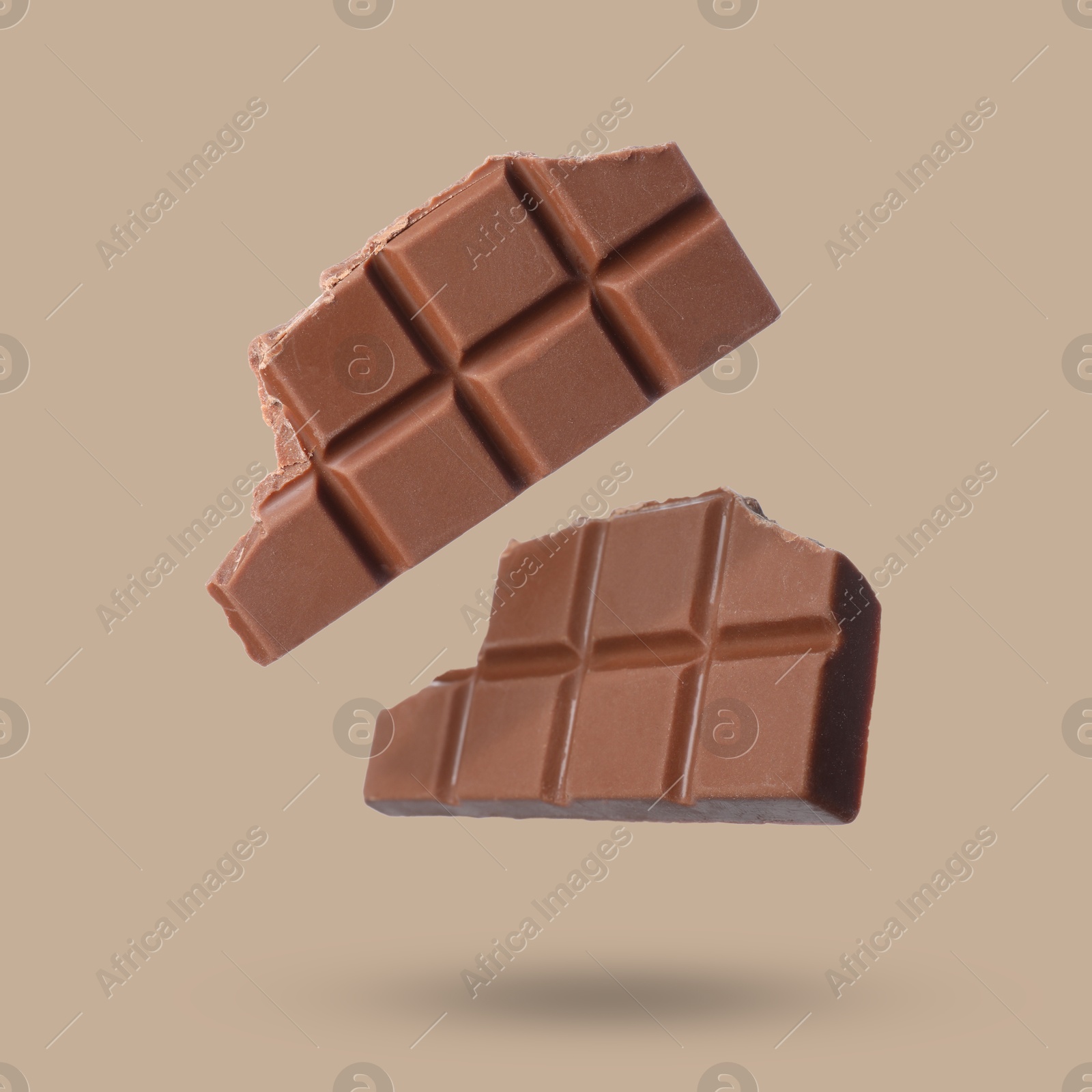 Image of Pieces of sweet chocolate falling on beige background