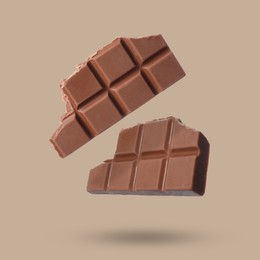 Image of Pieces of sweet chocolate falling on beige background