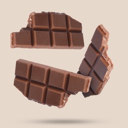 Image of Pieces of sweet chocolate falling on beige background