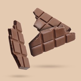 Image of Pieces of sweet chocolate falling on beige background