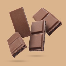 Image of Pieces of sweet chocolate falling on dark beige background