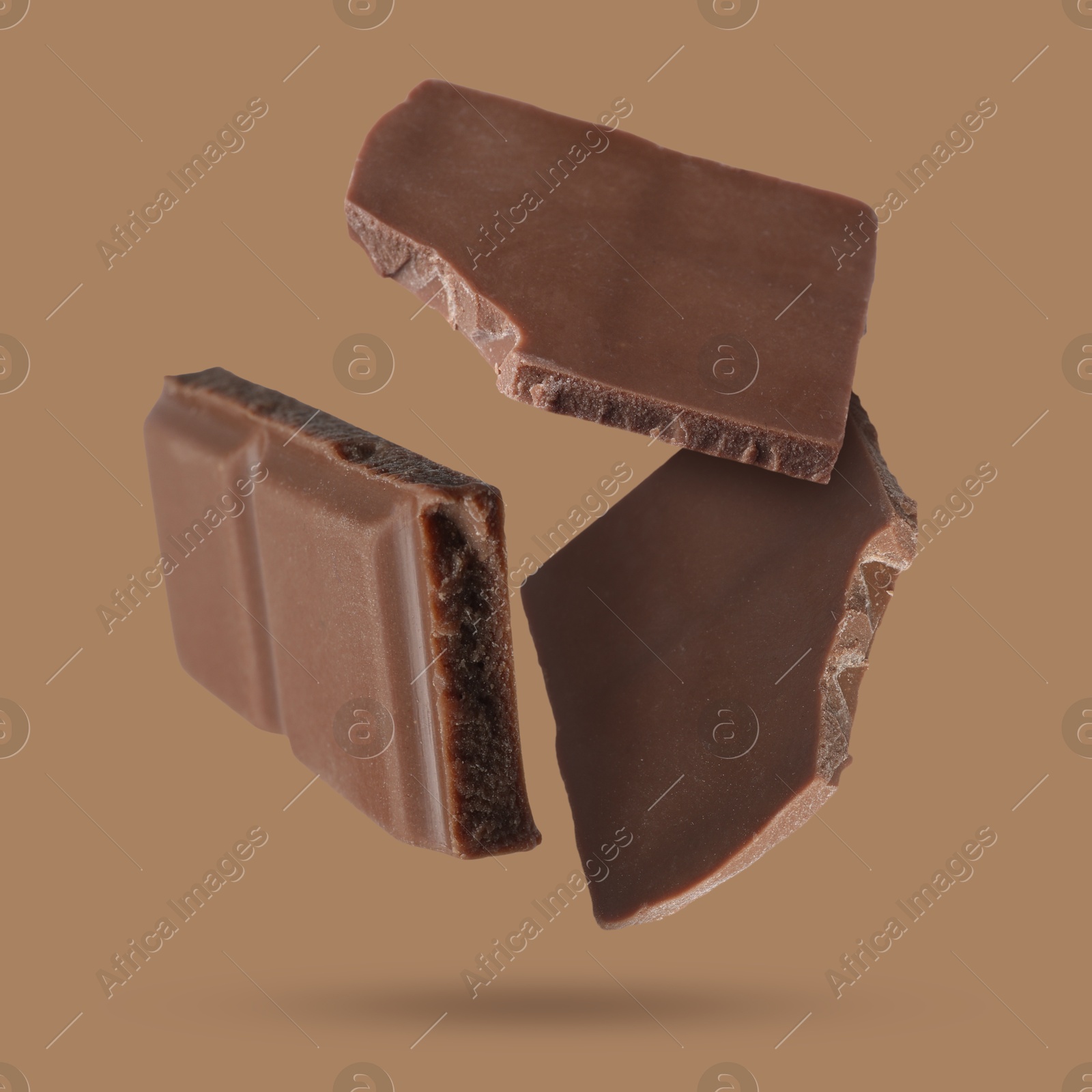 Image of Pieces of sweet chocolate falling on color background