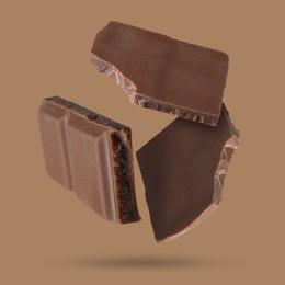 Image of Pieces of sweet chocolate falling on color background