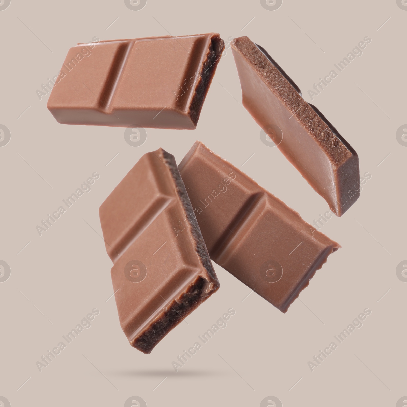 Image of Pieces of sweet chocolate falling on beige background