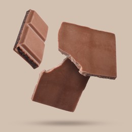 Image of Pieces of sweet chocolate falling on beige background