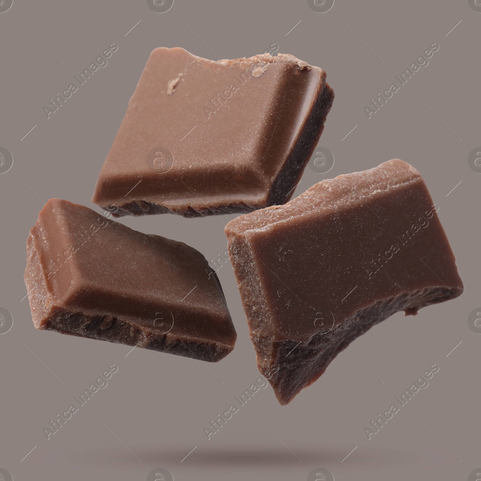 Image of Pieces of sweet chocolate falling on grey background