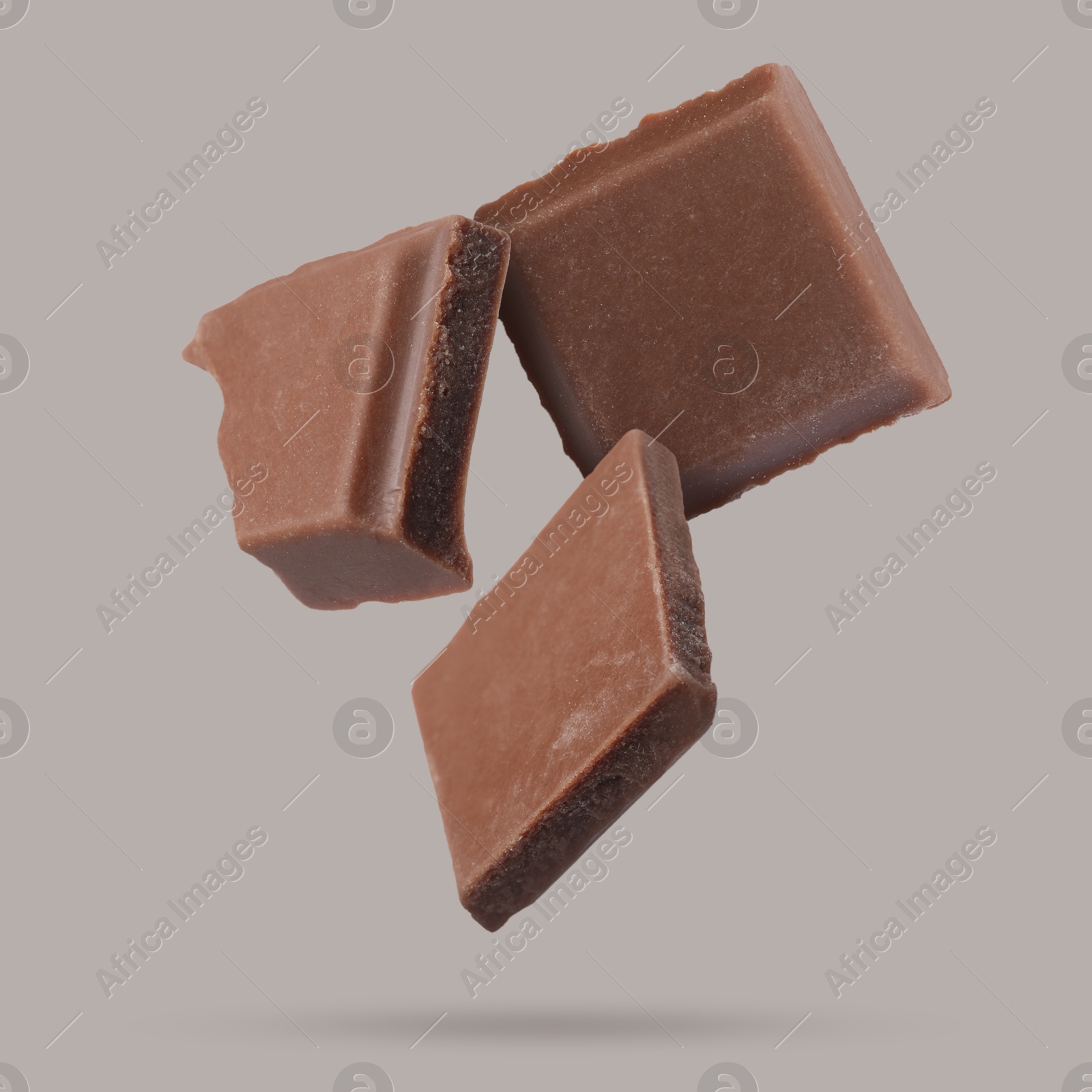 Image of Pieces of sweet chocolate falling on grey background