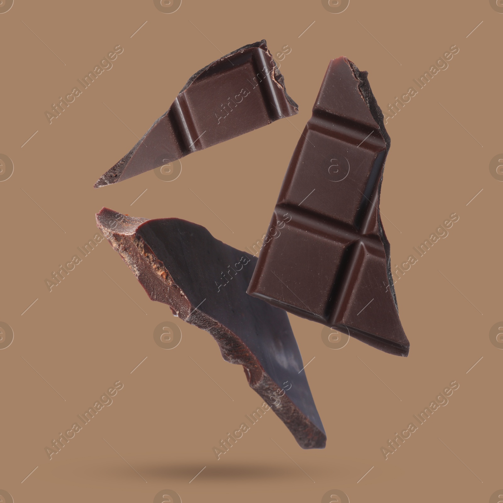 Image of Pieces of sweet chocolate falling on color background