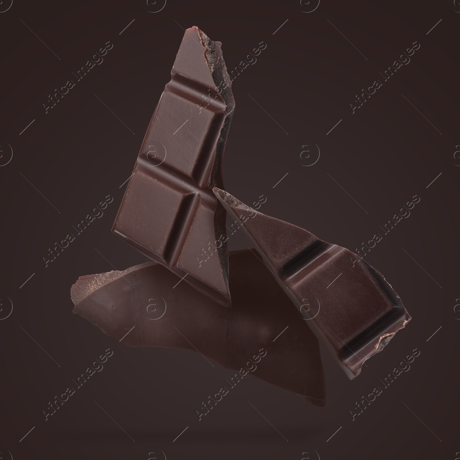 Image of Pieces of sweet chocolate falling on dark background