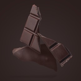 Image of Pieces of sweet chocolate falling on dark background