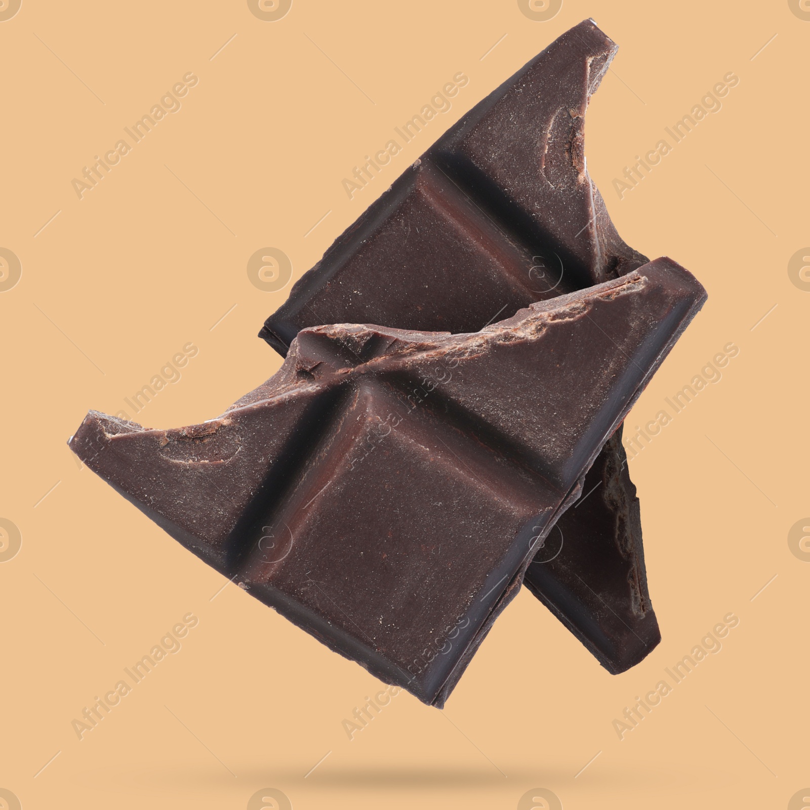 Image of Pieces of sweet chocolate falling on dark beige background