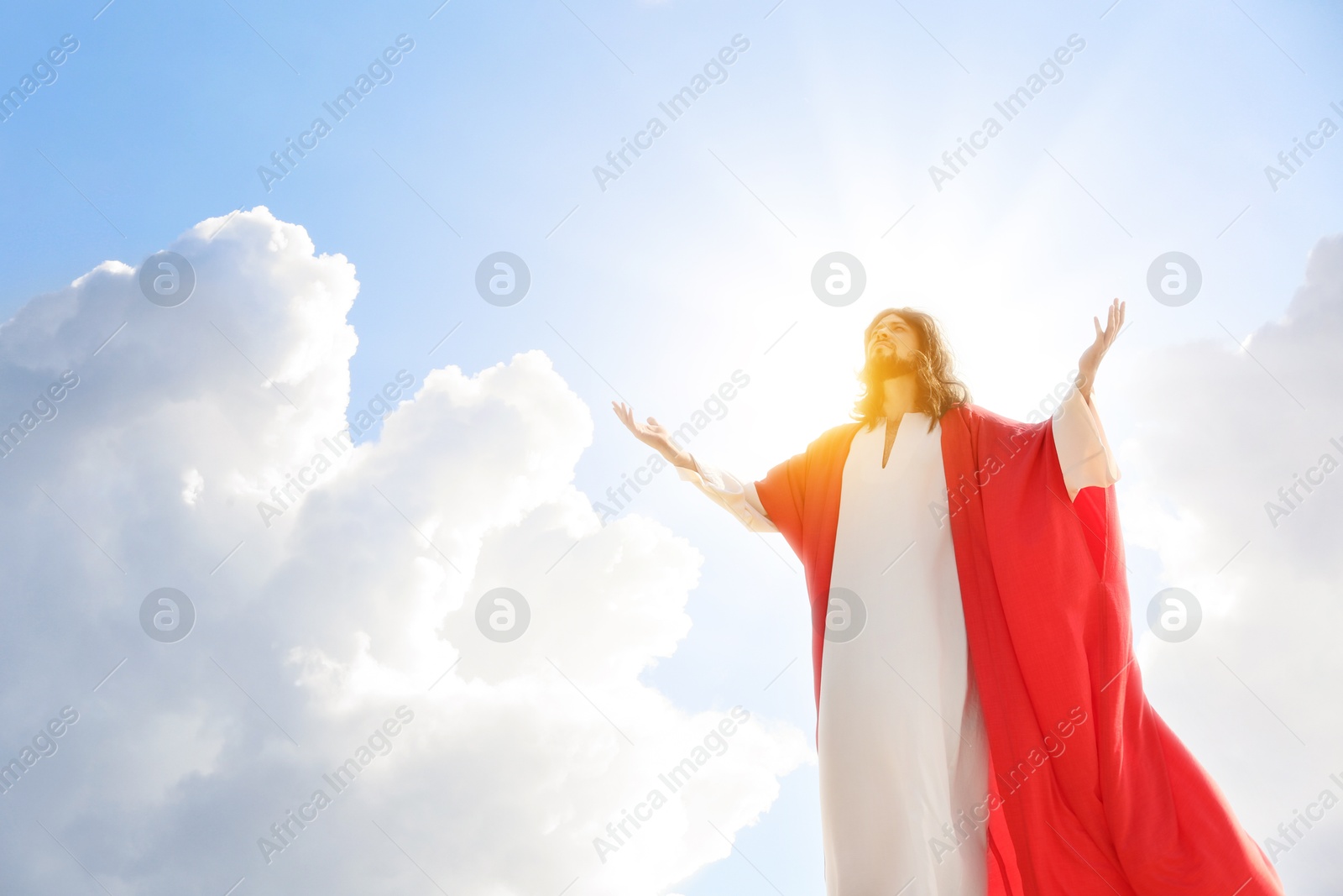 Image of Jesus Christ in sunlight among clouds in sky