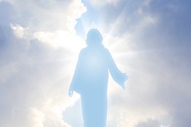 Silhouette of Jesus Christ in sunlight among clouds in sky