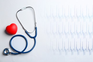 Image of Red decorative heart, stethoscope and electrocardiogram on white background, top view