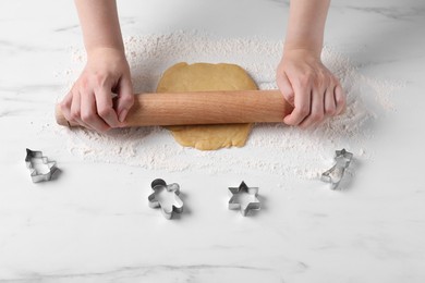 Photo of Woman rolling raw dough at white marble table, closeup