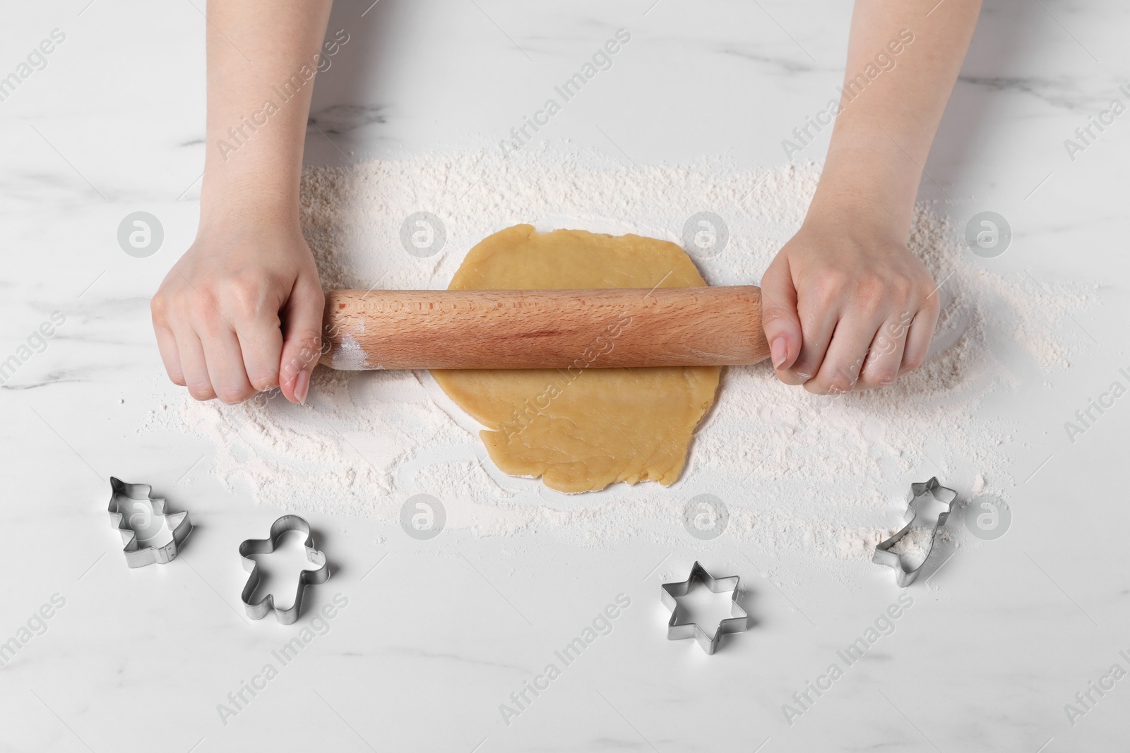 Photo of Woman rolling raw dough at white marble table, top view