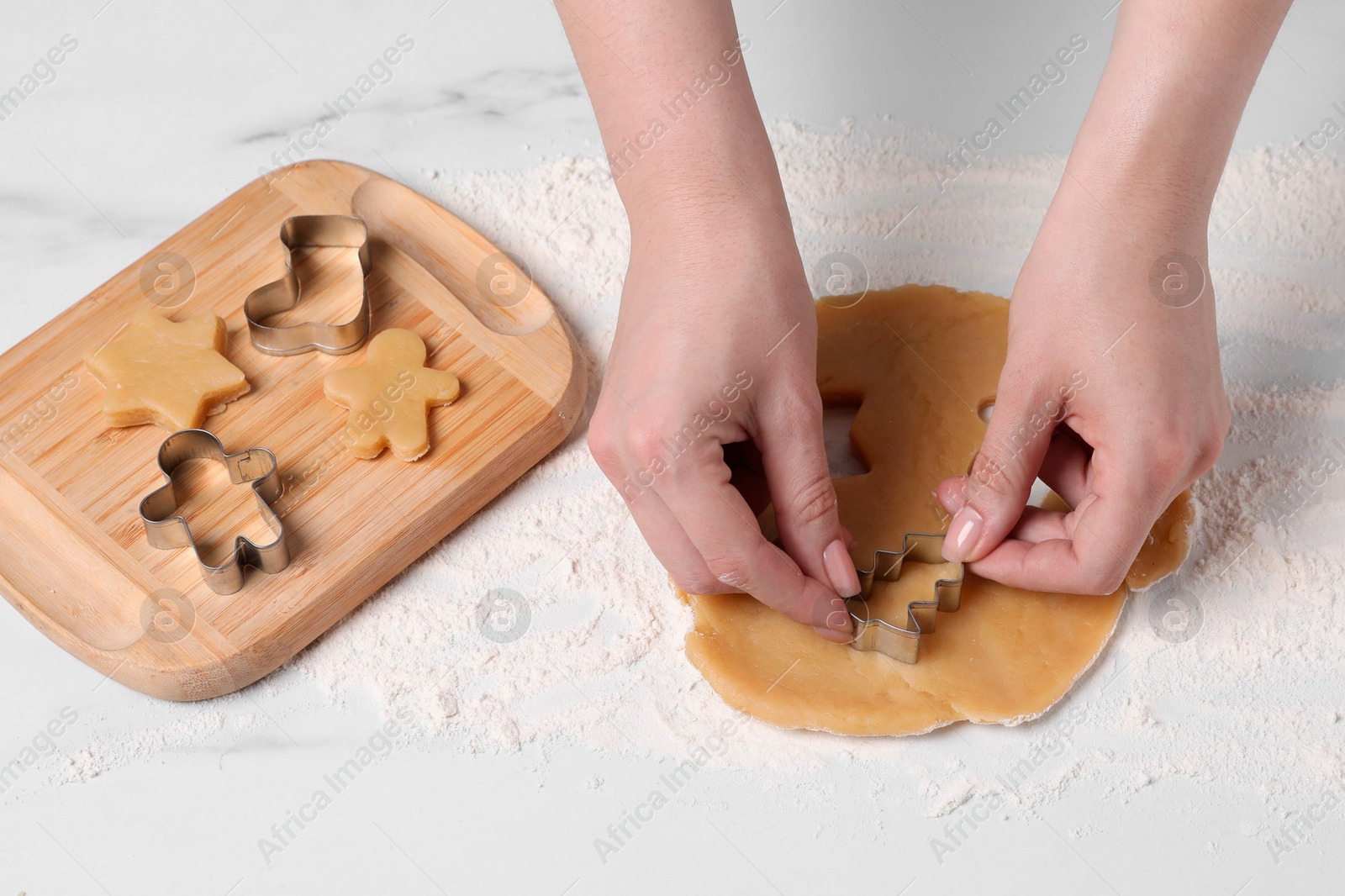 Photo of Woman making cookies with cutters at white marble table, closeup