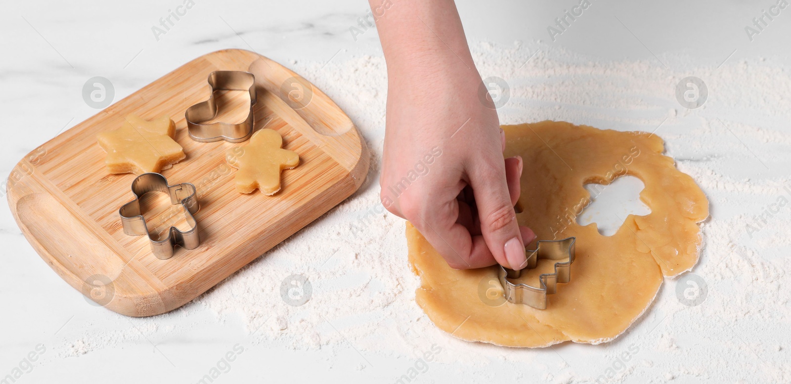 Photo of Woman making cookies with cutters at white marble table, closeup