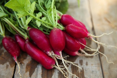 Photo of Bunch of freshly harvested radishes on wooden table, closeup