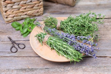 Photo of Different aromatic herbs and scissors on wooden table