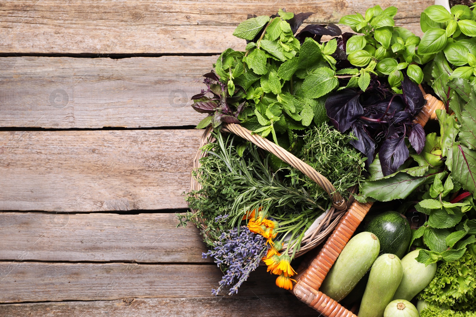 Photo of Different aromatic herbs and vegetables on wooden table, top view. Space for text