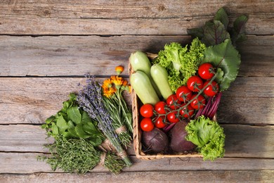 Photo of Different aromatic herbs and vegetables on wooden table, top view