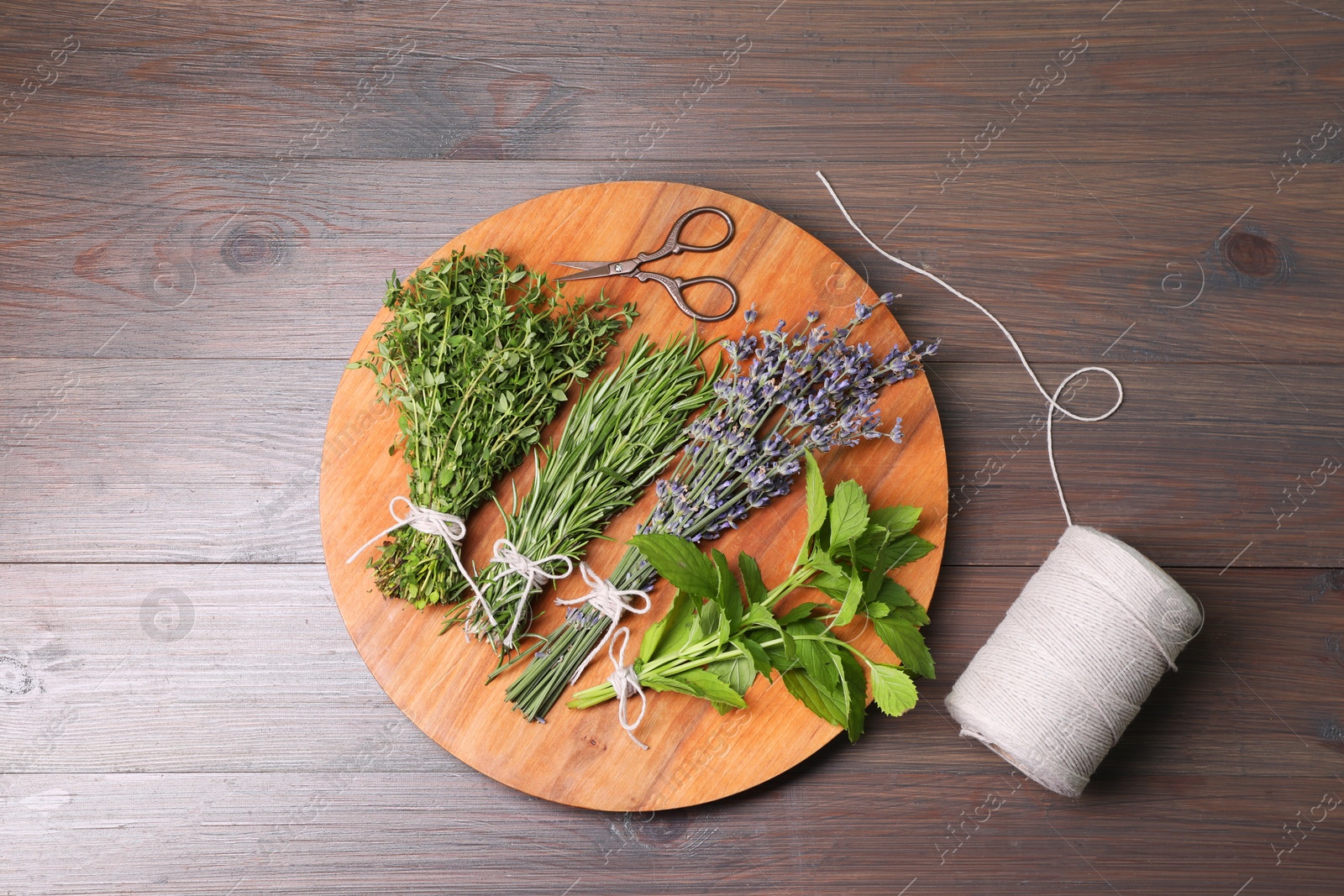 Photo of Different aromatic herbs, thread and scissors on wooden table, top view