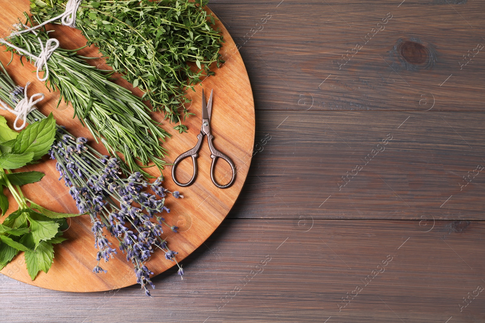 Photo of Different aromatic herbs and scissors on wooden table, top view. Space for text