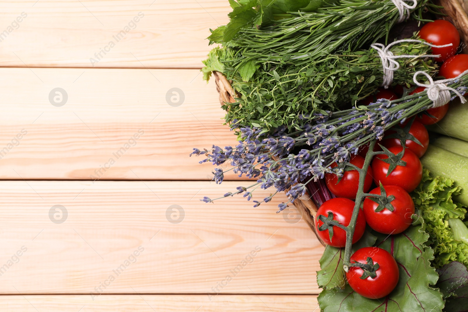 Photo of Different aromatic herbs and vegetables on wooden table, above view. Space for text