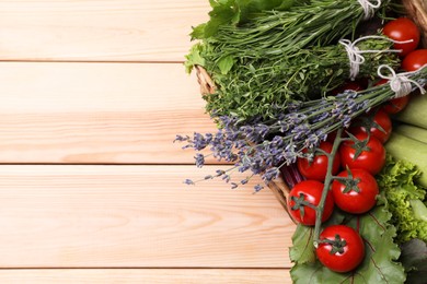 Photo of Different aromatic herbs and vegetables on wooden table, above view. Space for text