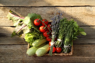 Photo of Different aromatic herbs and vegetables on wooden table, top view