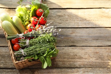 Photo of Different aromatic herbs and vegetables on wooden table. Space for text