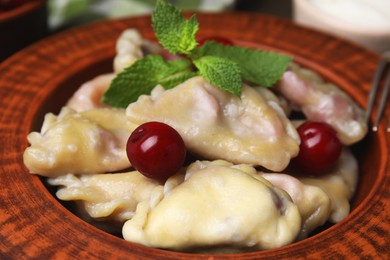 Photo of Traditional Ukrainian dumplings (varenyky) with cherries on plate, closeup