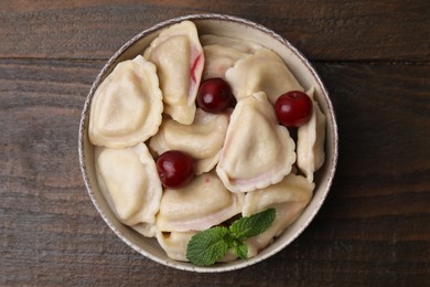 Traditional Ukrainian dumplings (varenyky) with cherries on wooden table, top view