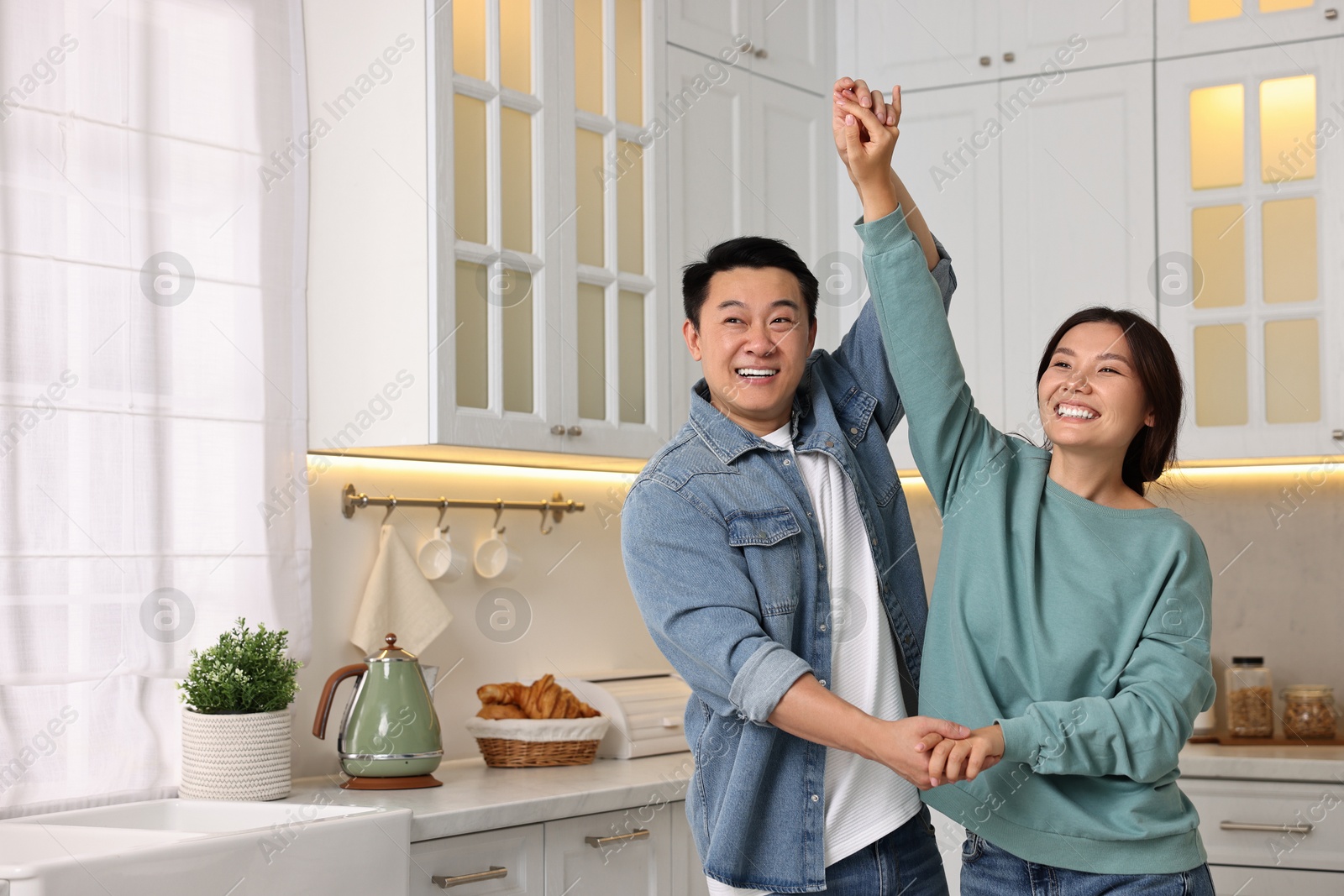 Photo of Happy lovely couple dancing together in kitchen