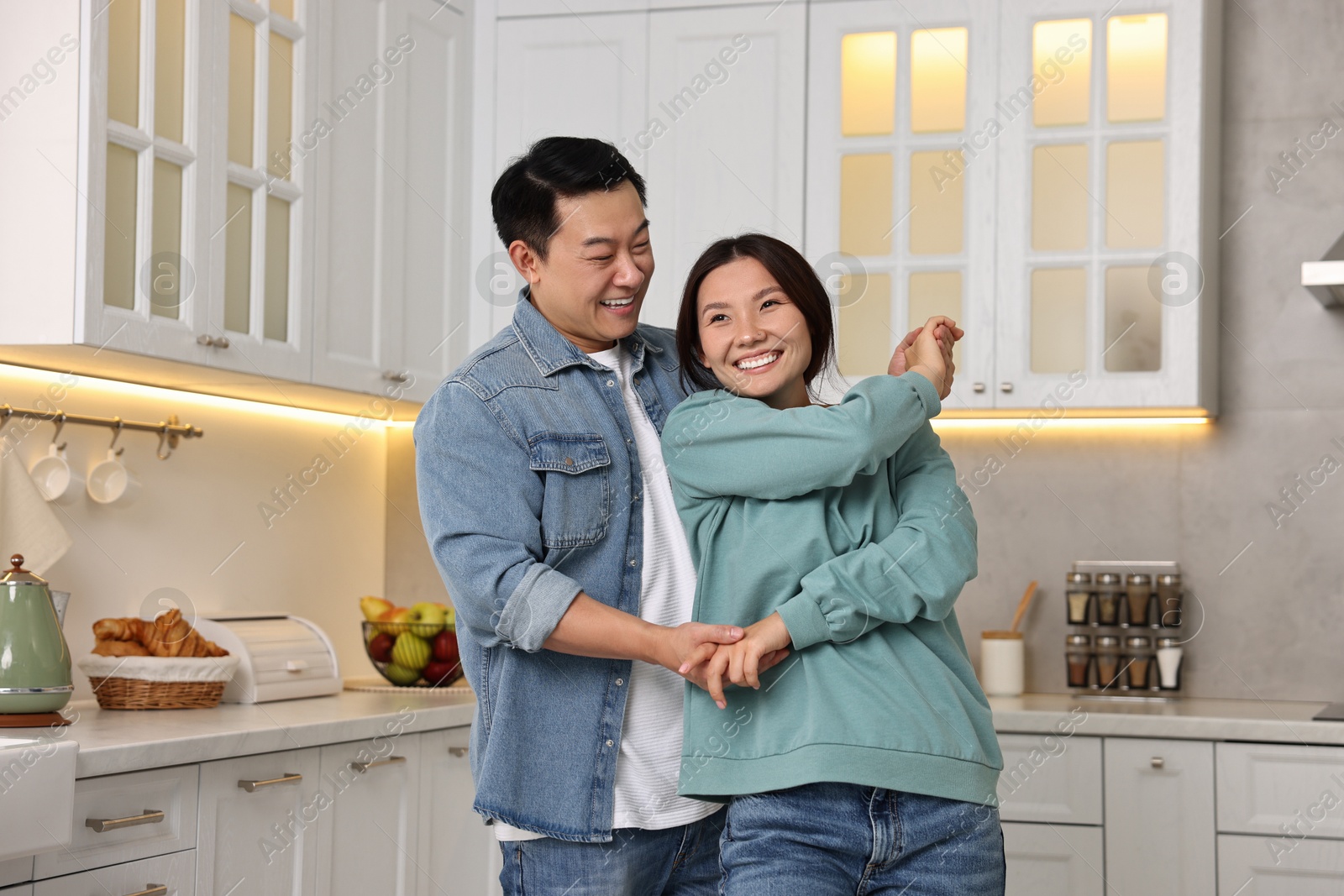 Photo of Happy lovely couple dancing together in kitchen