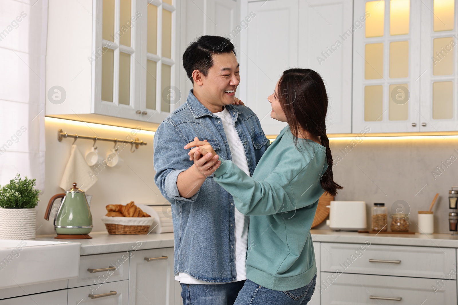 Photo of Happy lovely couple dancing together in kitchen