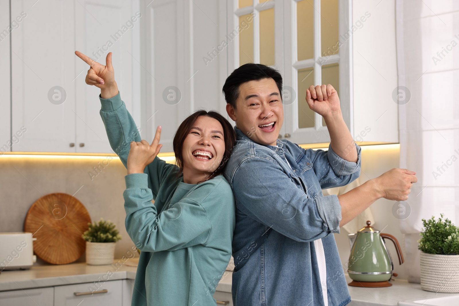 Photo of Happy lovely couple dancing together in kitchen