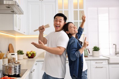 Happy lovely couple singing together while cooking in kitchen