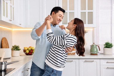 Happy lovely couple dancing together in kitchen