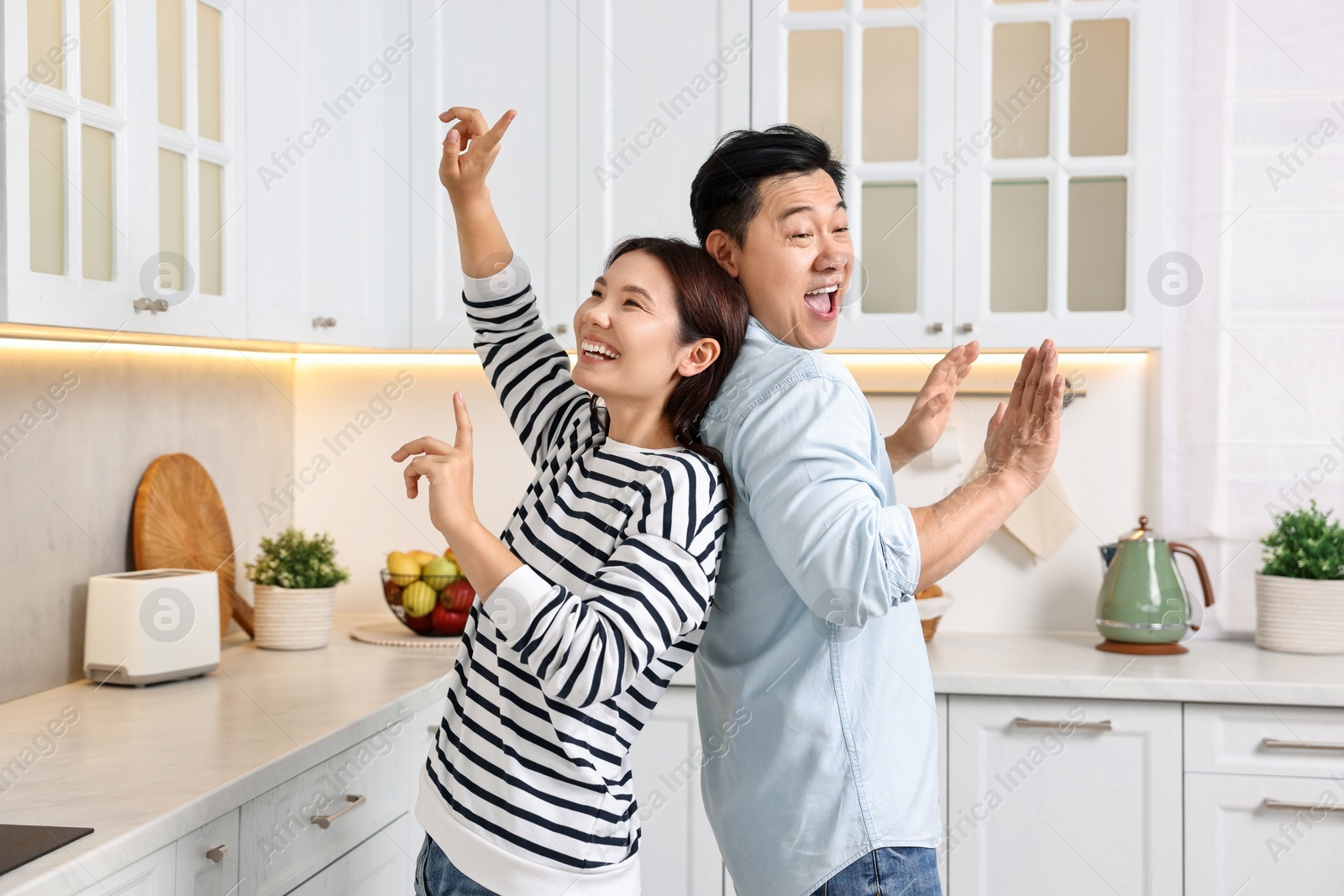 Photo of Happy lovely couple dancing together in kitchen