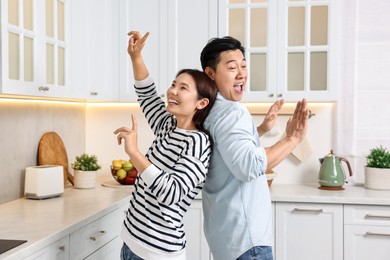 Happy lovely couple dancing together in kitchen