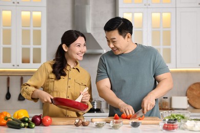 Happy lovely couple cooking together in kitchen